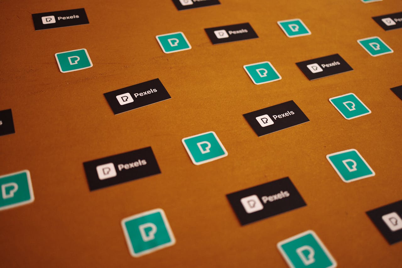 Pexels logos and stickers scattered on a brown background in a creative pattern.